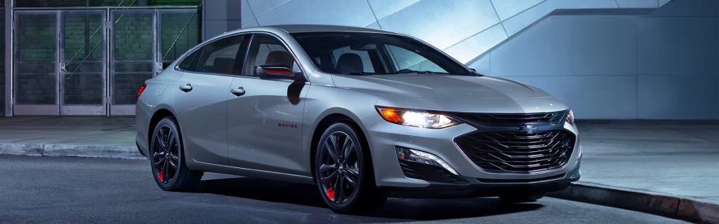 The 2025 Chevy Malibu parked in front of a sidewalk