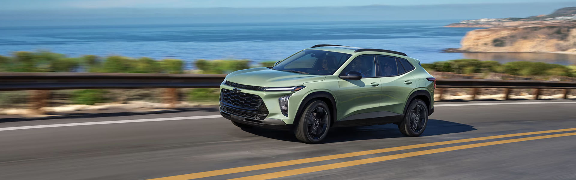 2025 Chevrolet Trax driving on a coastal highway with ocean views and cliffs in the background
