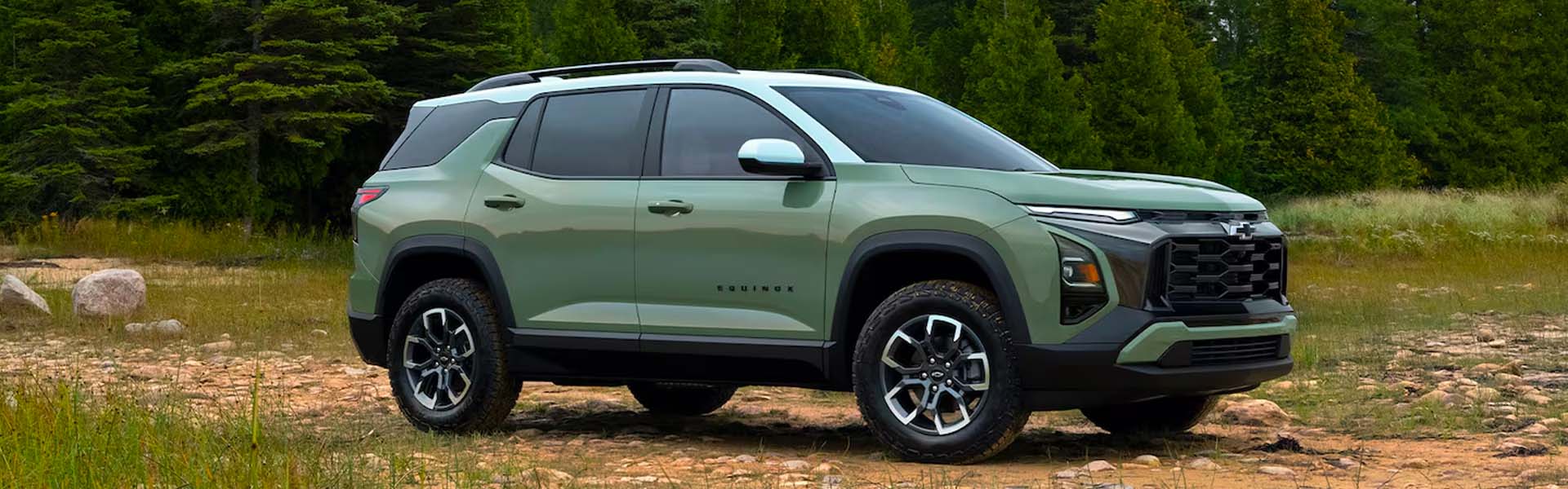 2026 Chevrolet Equinox compact crossover SUV in green with black roof rails and aggressive grille, parked in nature emphasizing adventure-ready performance and modern SUV styling