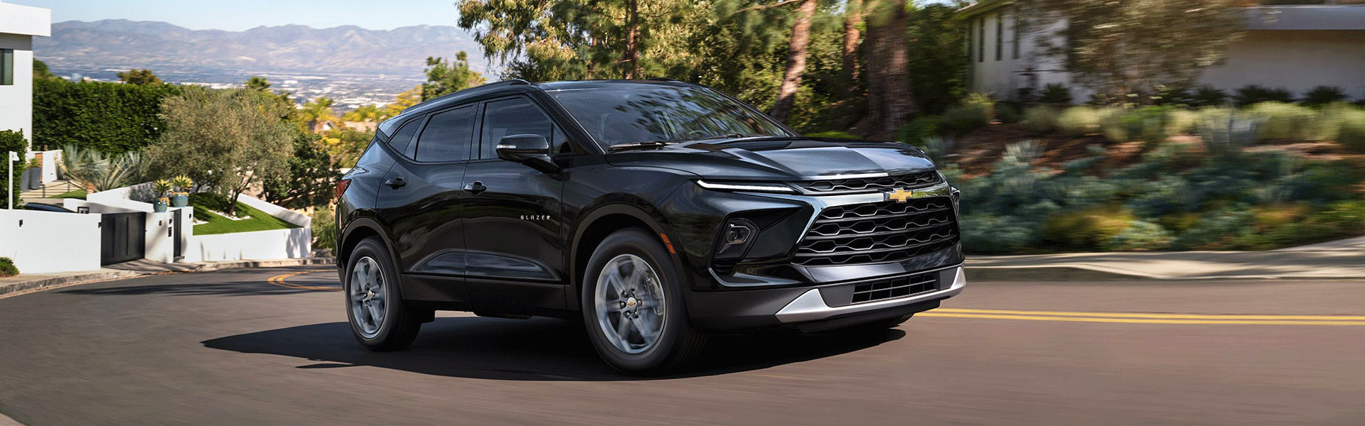 2026 Chevy Blazer midsize SUV driving through a scenic suburban neighborhood.